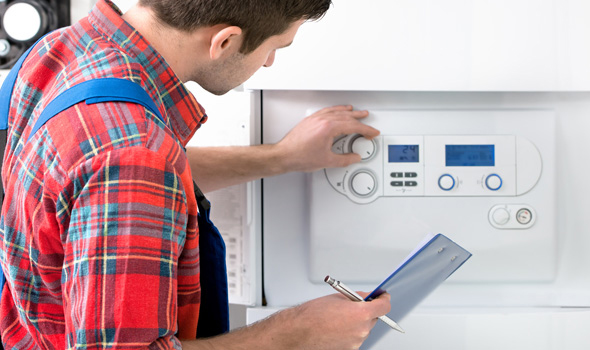 A worker adjusts the temperature on an energy efficient boiler.